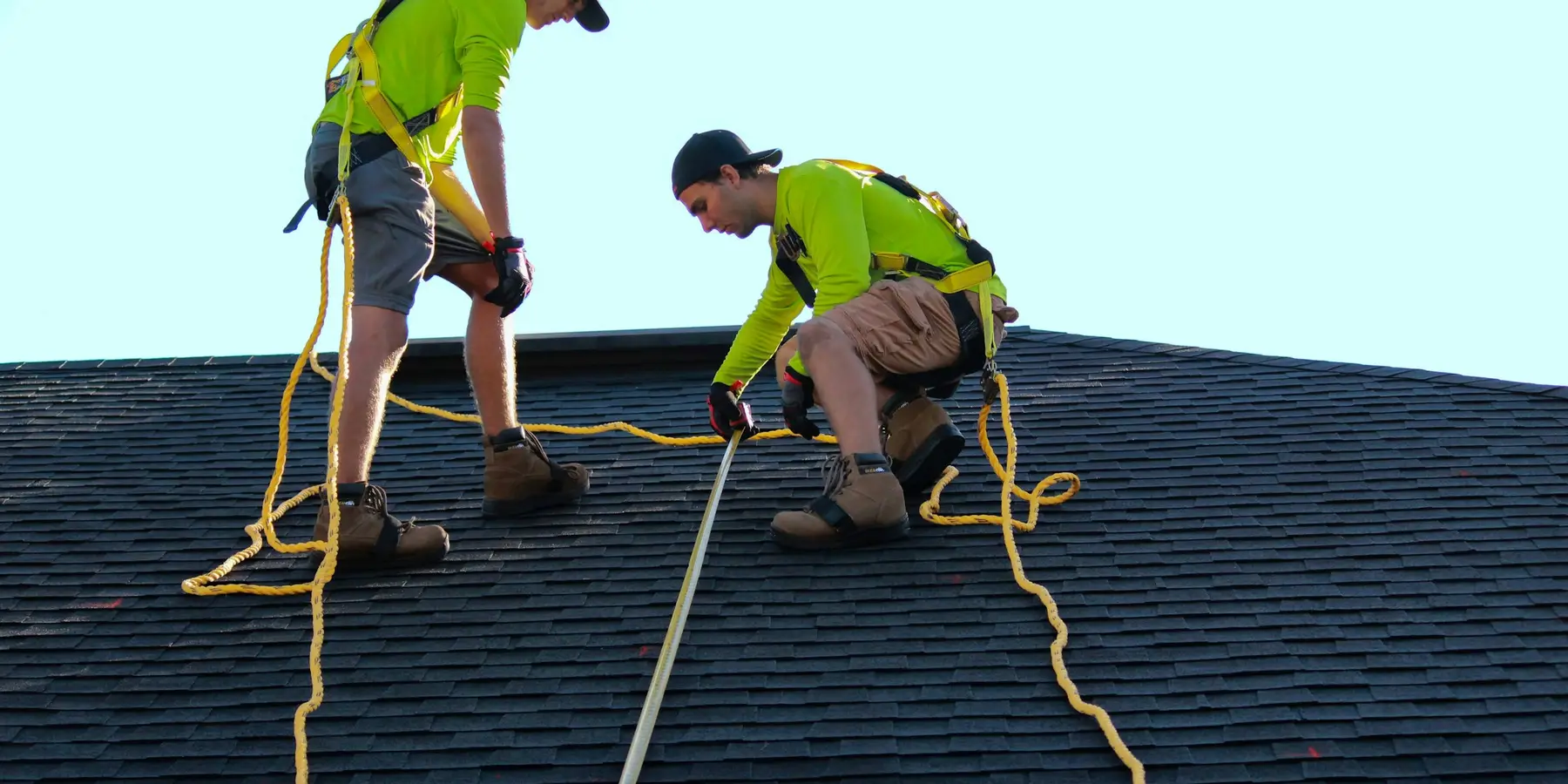 Two roofers measuring a shingle roof