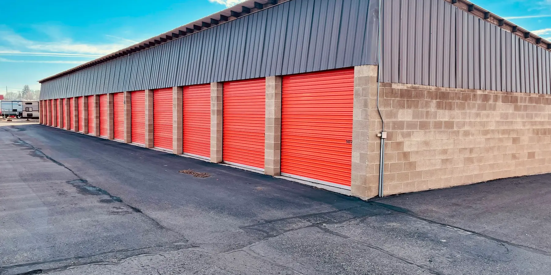 A row of drive-up storage units under a clear sky