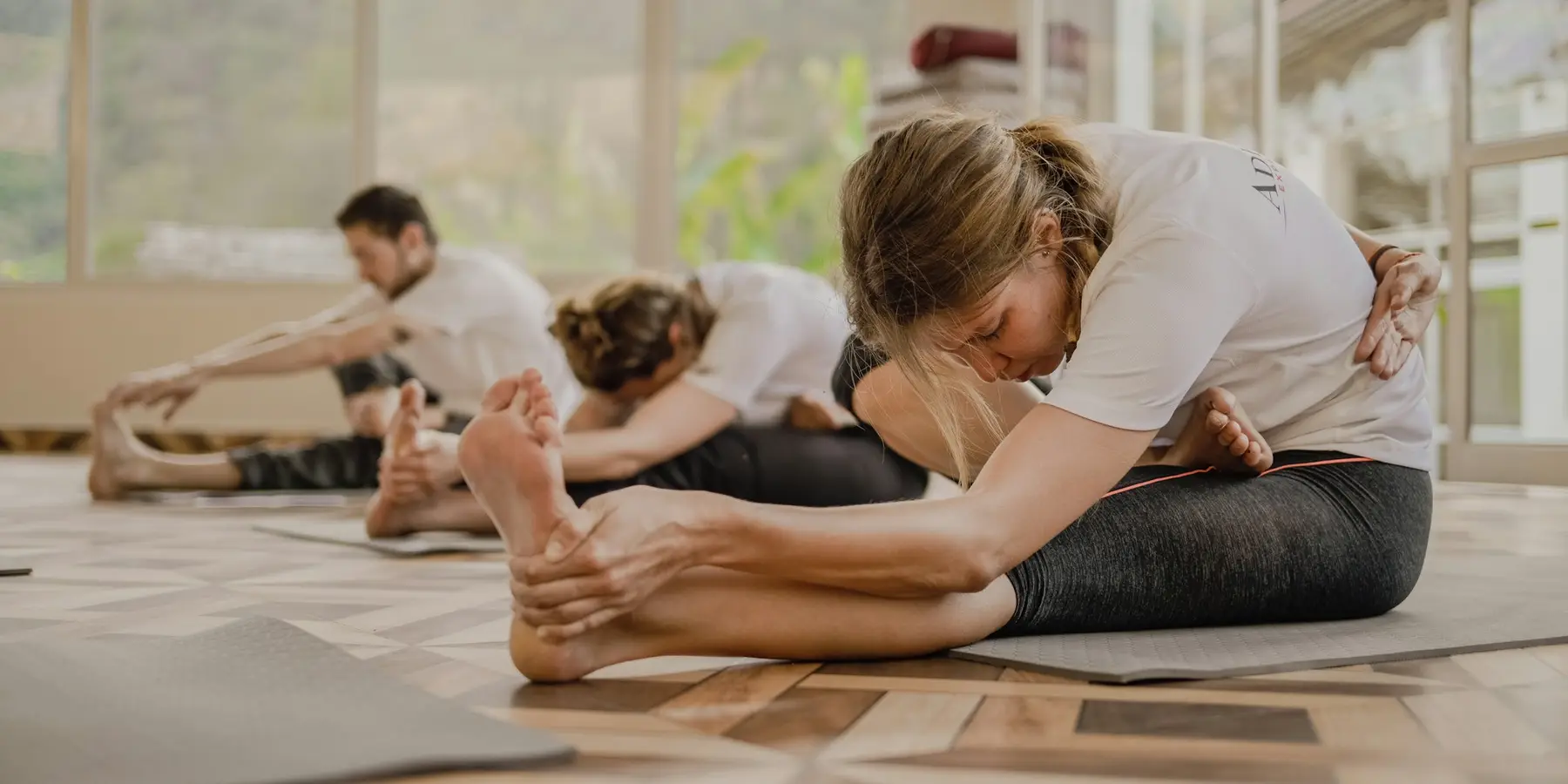A yoga class stretching in a sunlit studio